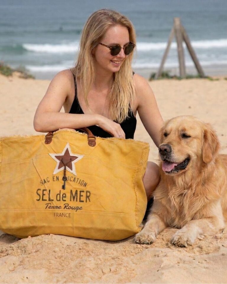sac plage xl jaune Grand sac de plage XXL "Sel de Mer" coloris jaune safran posé sur le sable à côté d'un chien Golden Retriever. Cabas éco-responsable en toile recyclée et anses en cuir, idéal pour les vacances et les sorties estivales