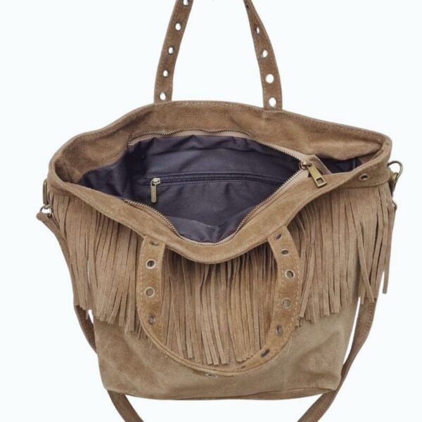 Cabas en daim taupe avec franges et œillets dorés, porté à l'épaule