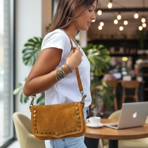 Femme portant un sac en daim camel Zosha Collection, look bohème chic avec jean et t-shirt blanc, accessoire mode tendance 2025
