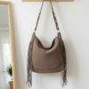 Sac en daim taupe à franges porté en bandoulière, style bohème chic