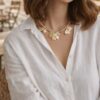 Collier doré Mile mila avec cordon tressé, chaîne mêlée et breloques feuilles sur un modèle portant une chemise blanche