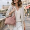 Femme style effortless chic portant le sac Lucile rose poudré à franges en daim, porté épaule, dans une rue de Biarritz